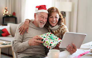 Active Aging Couple Opening Presents via Video Call